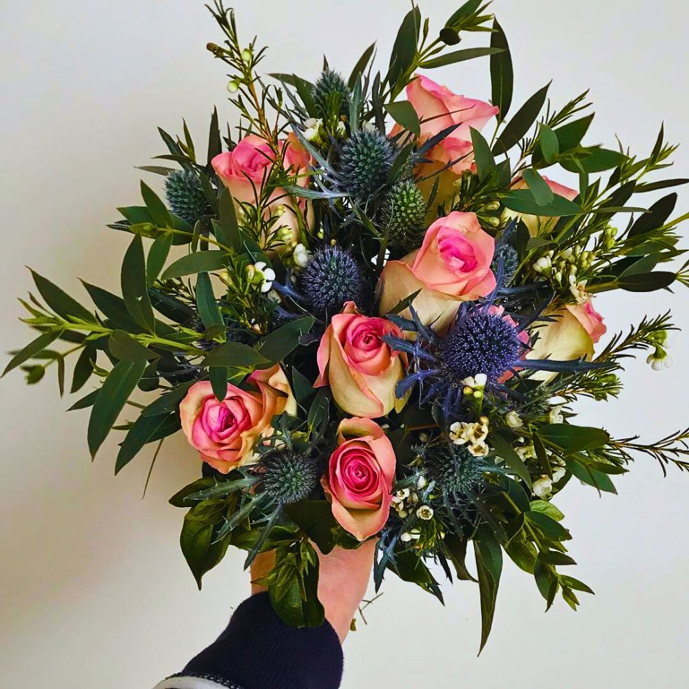 Sea holly design with roses and decorative greens sea holly arranged around rose in a bouquet setting - Sea holly design with roses and decorative greens