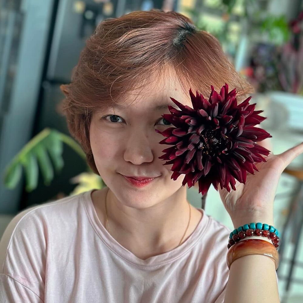 Lady holding one stem black Dahlia flower deep hues of black dahlia and its long stems make it prime among the list of most gorgeous flowers