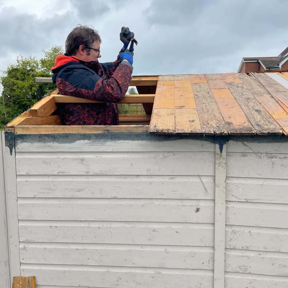 Man repairing shed roof structure Man repairing shed roof structure