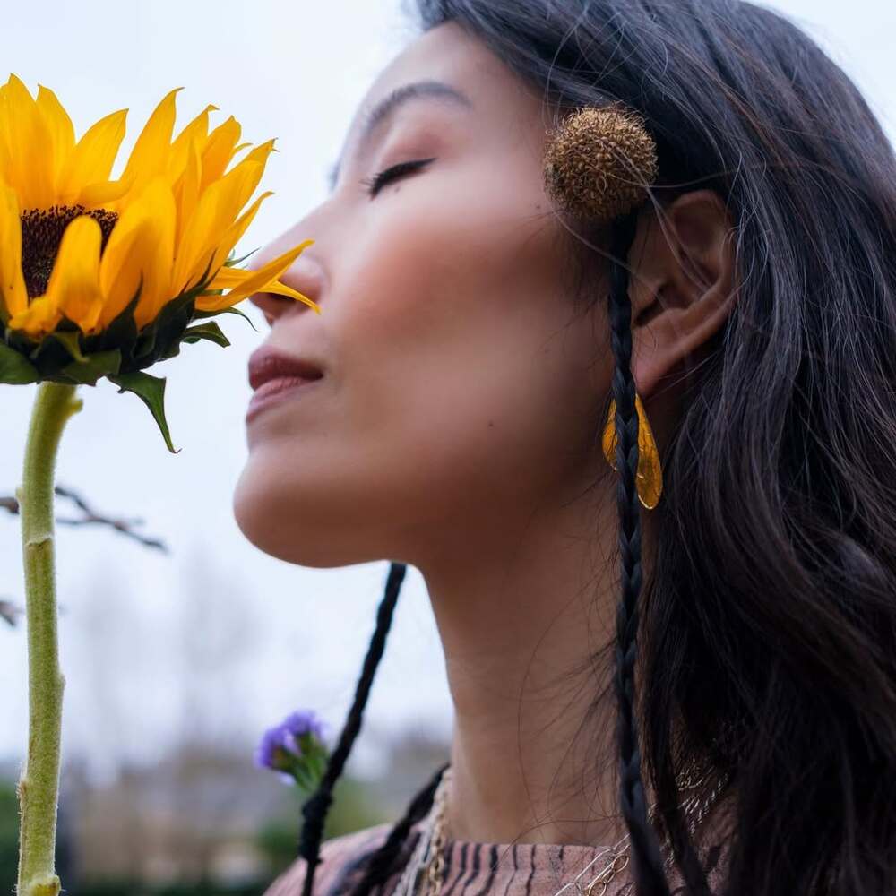 Woman peacefully smelling sunflower bloom