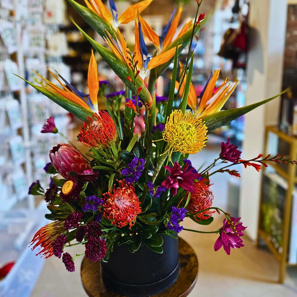 Tropical flower design Bird of Paradise with white roses and Monstera leaves in an arrangement