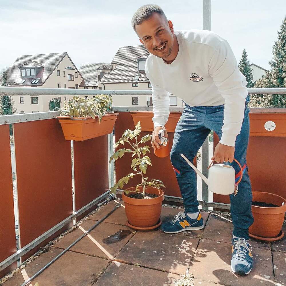 Man watering balcony potted plants Man watering balcony potted plants