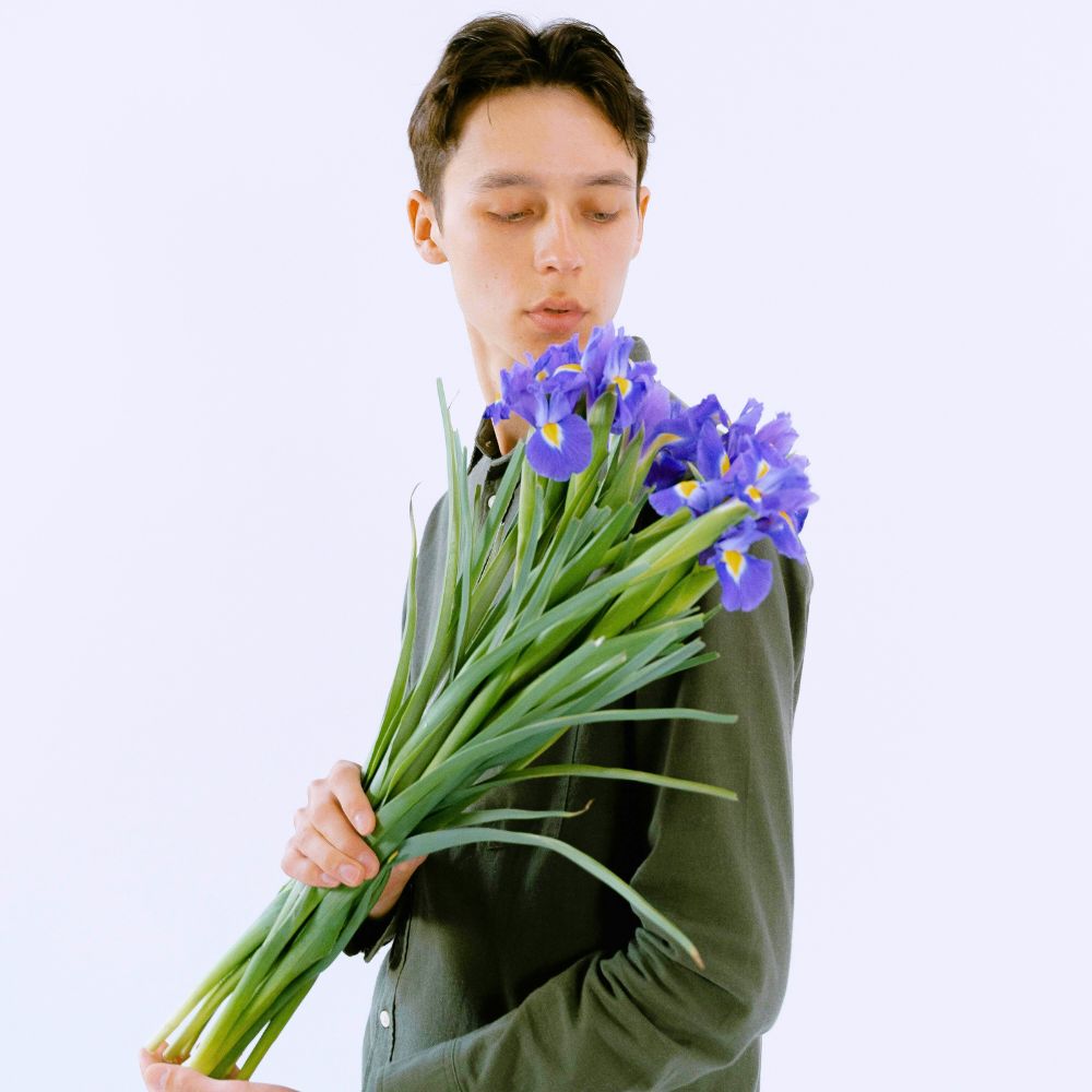 A gentleman holding a bunch of blue iris flowers Blue Irisi