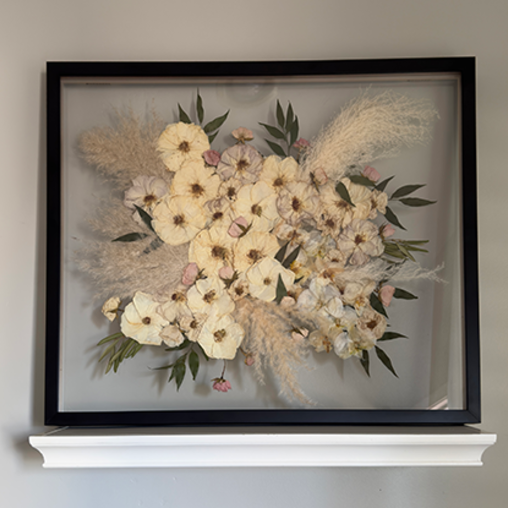 Pressed white wedding flowers in frame