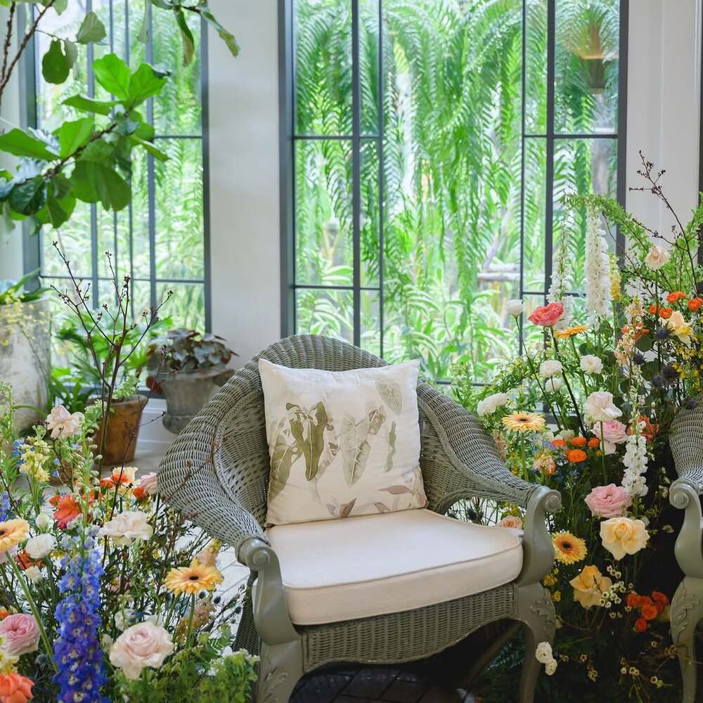 Elegant wicker chair among flowers Elegant wicker chair among flowers