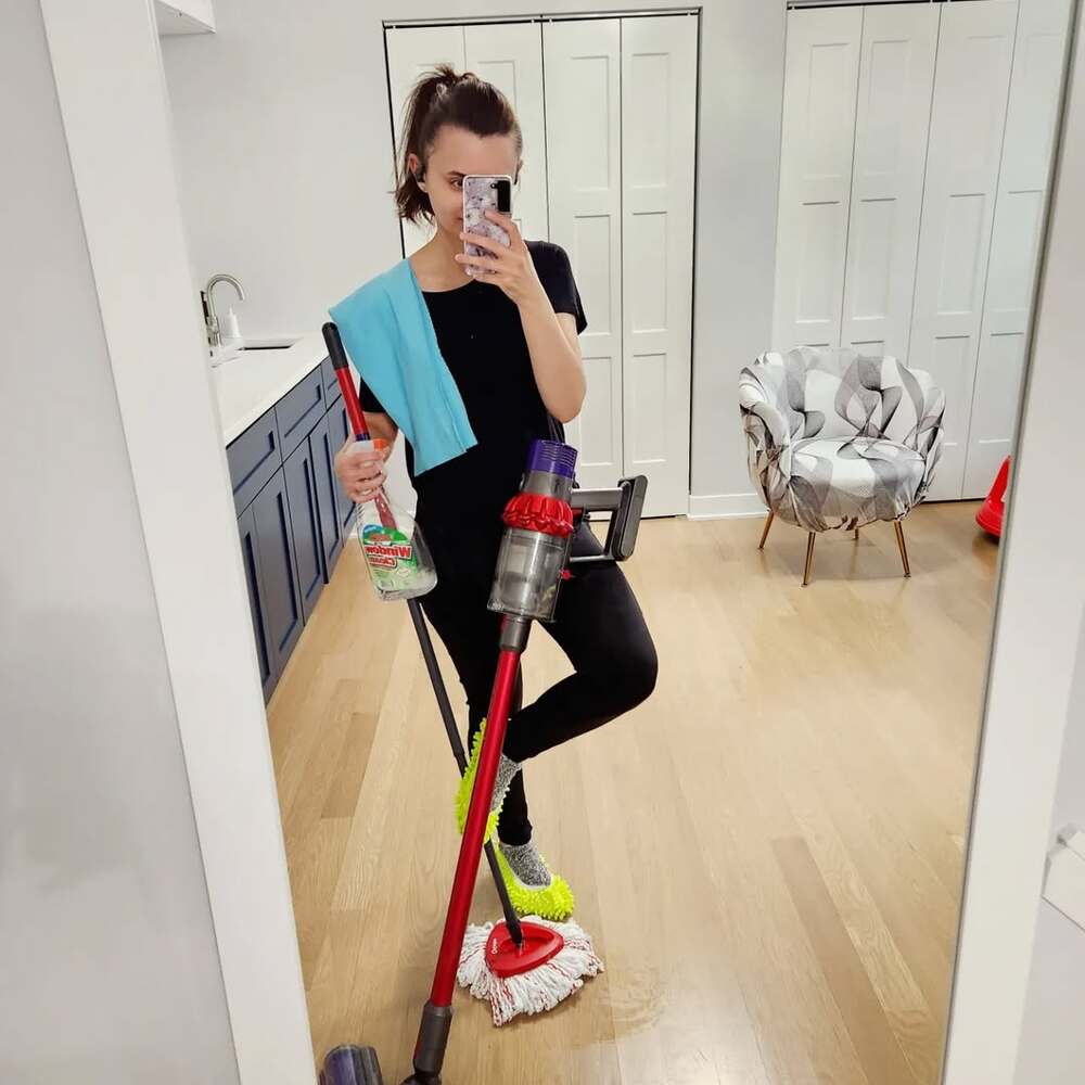 Woman poses with Dyson vacuum and cleaning supplies Woman poses with Dyson vacuum and cleaning supplies