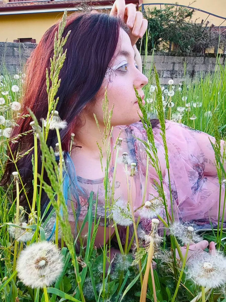 Dandelions woman posing for a photograph around dandelions in a home garden