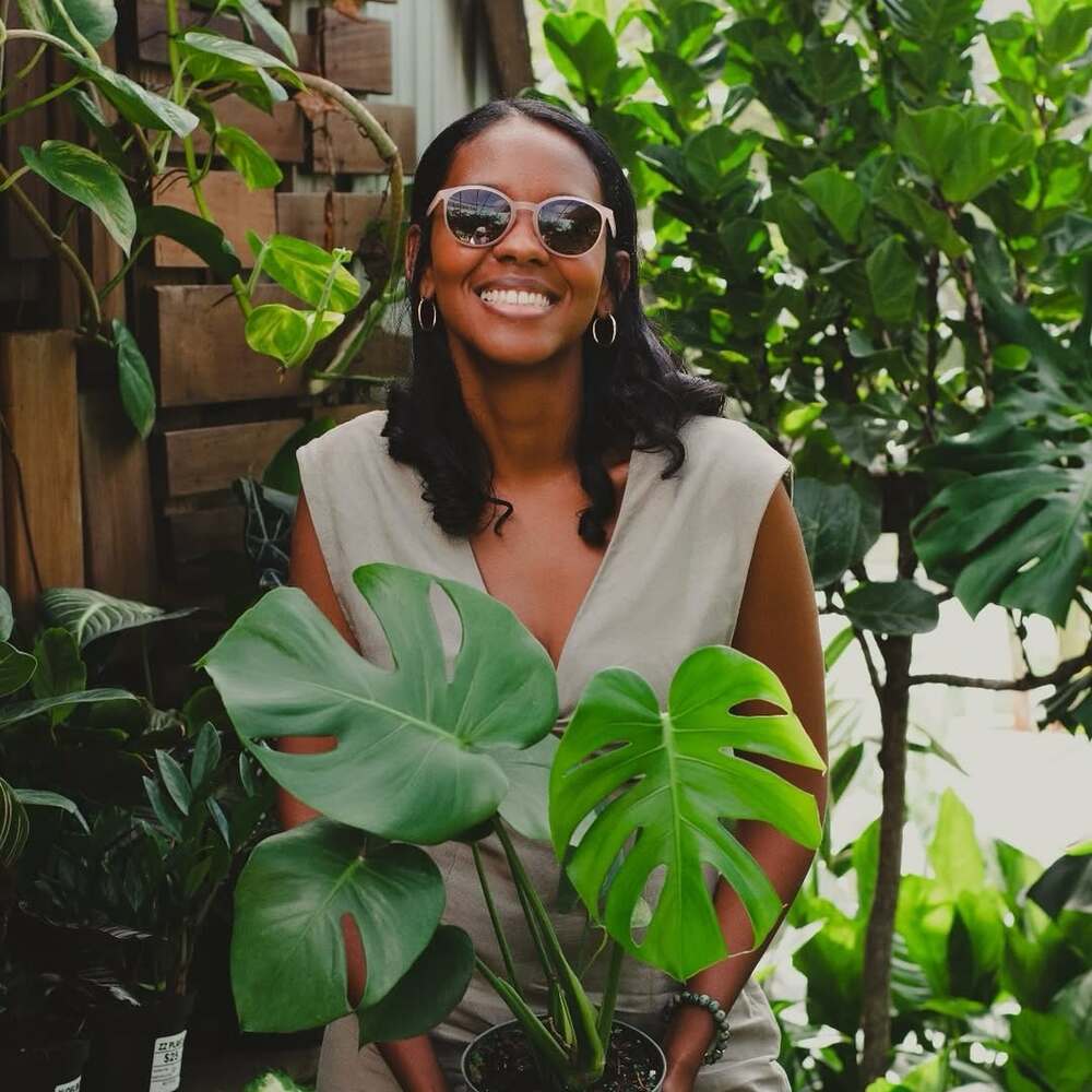 Woman holding Monstera plant smiling Woman holding Monstera plant smiling