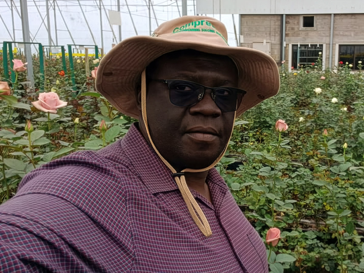 Fred Okinda with hat and sunglasses in greenhouse