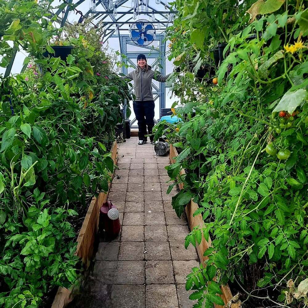 Woman standing in lush greenhouse Woman standing in lush greenhouse