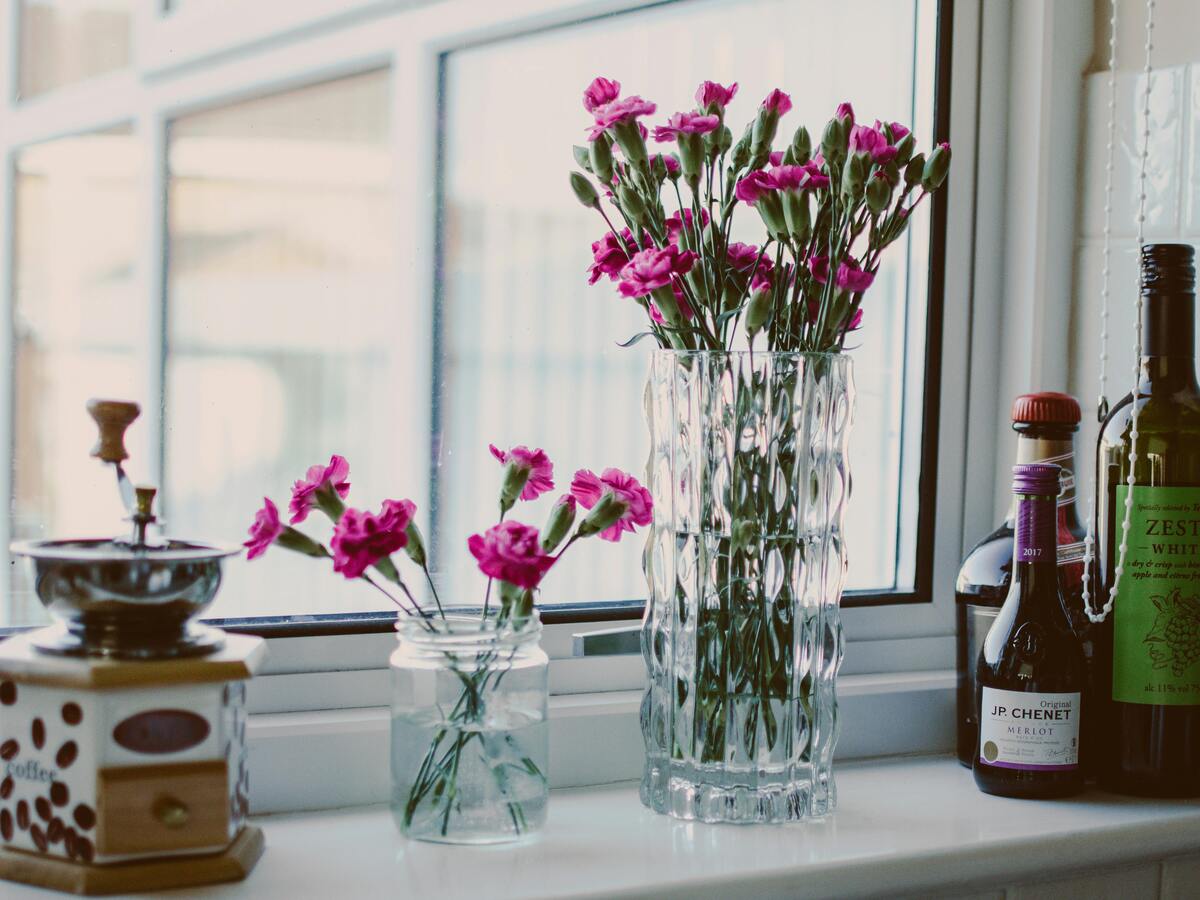 Pink flowers and wine bottles on sill Pink flowers and wine bottles on sill