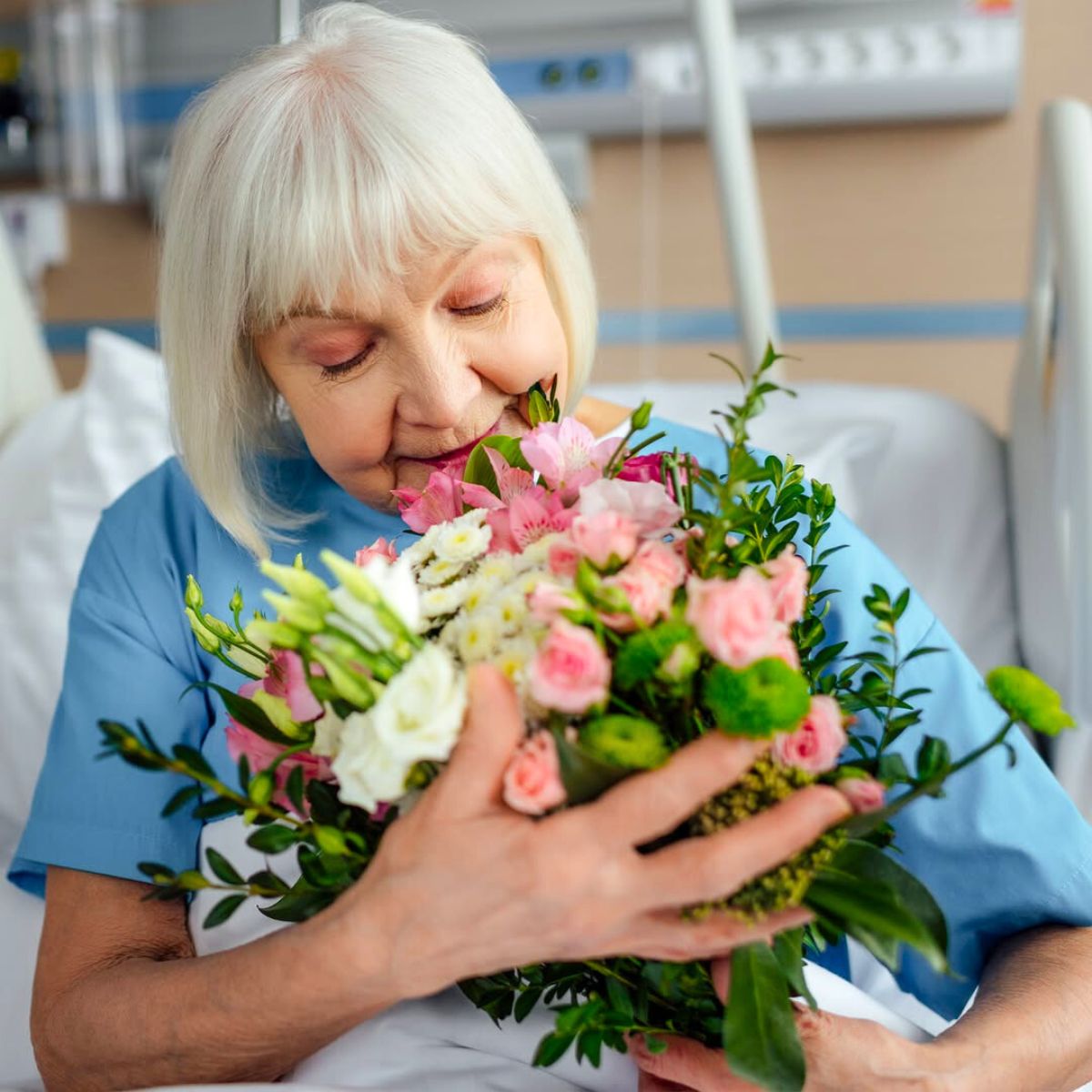 Elder woman in hospital with flowers Elder woman in hospital with flowers