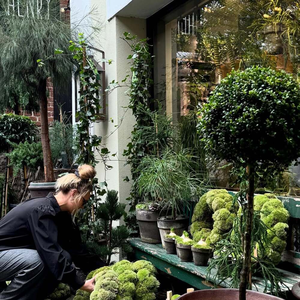 Florist arranging moss wreaths outside shop