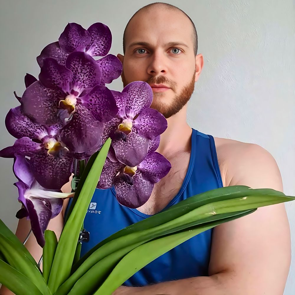 a man holding a pot of Blue Singapore Orchid, also known as the Blue Vanda