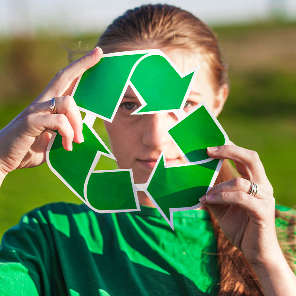 Girl looking through recycling logo