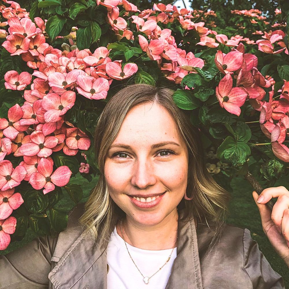 A lady poses for a picture in a pink dogwood bush