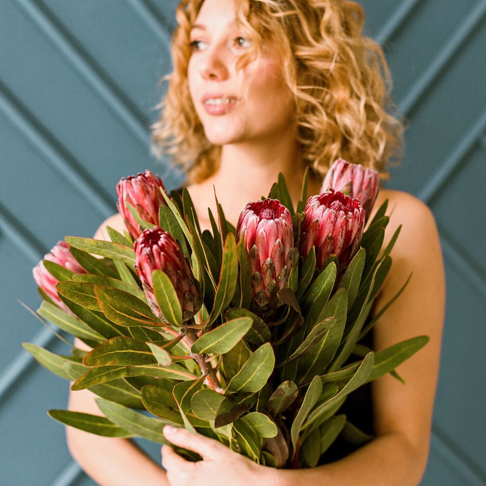 woman holding a bunch of proteas